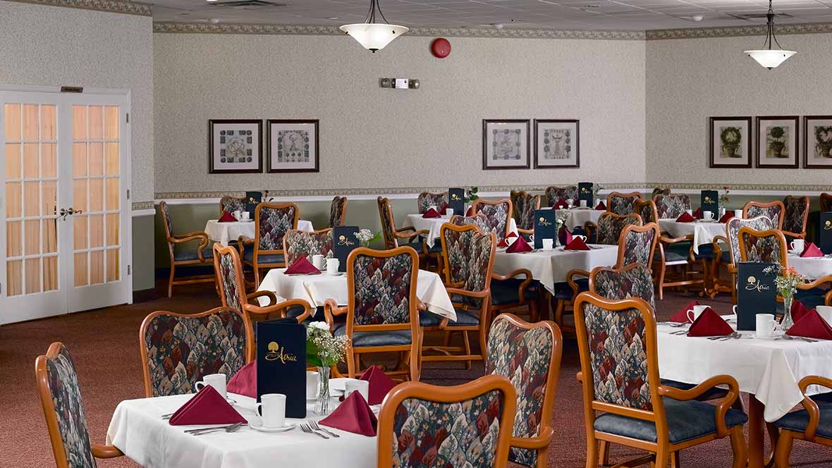 A well-decorated dining room with multiple tables and chairs, set for a meal.