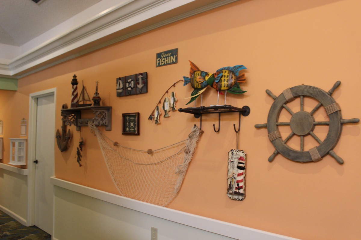 A wall adorned with nautical-themed decor, including a ship wheel, colorful fish, anchors, seashells, and a decorative fishnet.