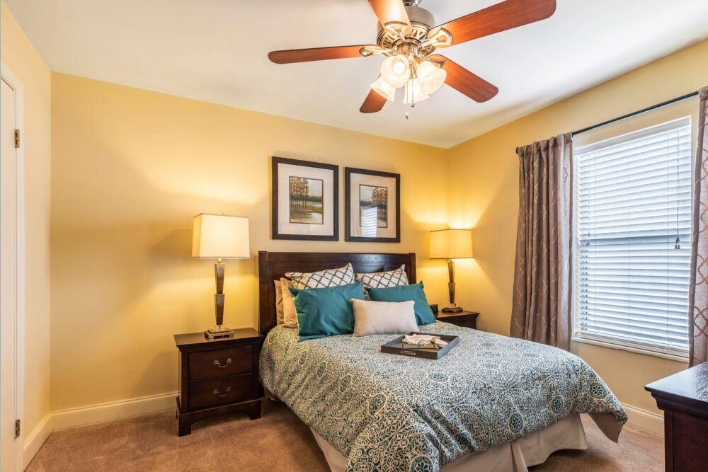A cozy bedroom featuring elegant decor with a ceiling fan, framed artwork, and ambient lighting from bedside lamps.