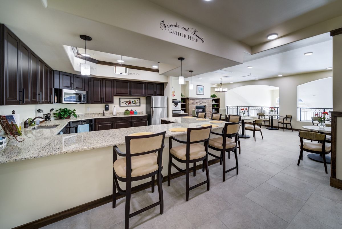 A modern kitchen with an open dining area featuring bar stools at the island and stylish pendant lighting.