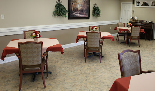 A cozy dining area featuring tables with red tablecloths and elegant chairs, complemented by decorative plants on the walls.