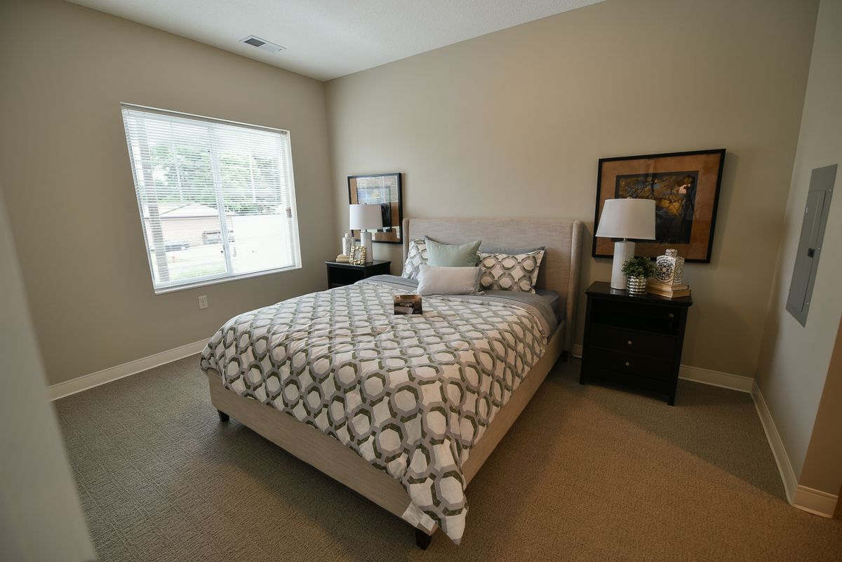 A cozy bedroom with a neatly made bed, nightstands, and decorative elements.