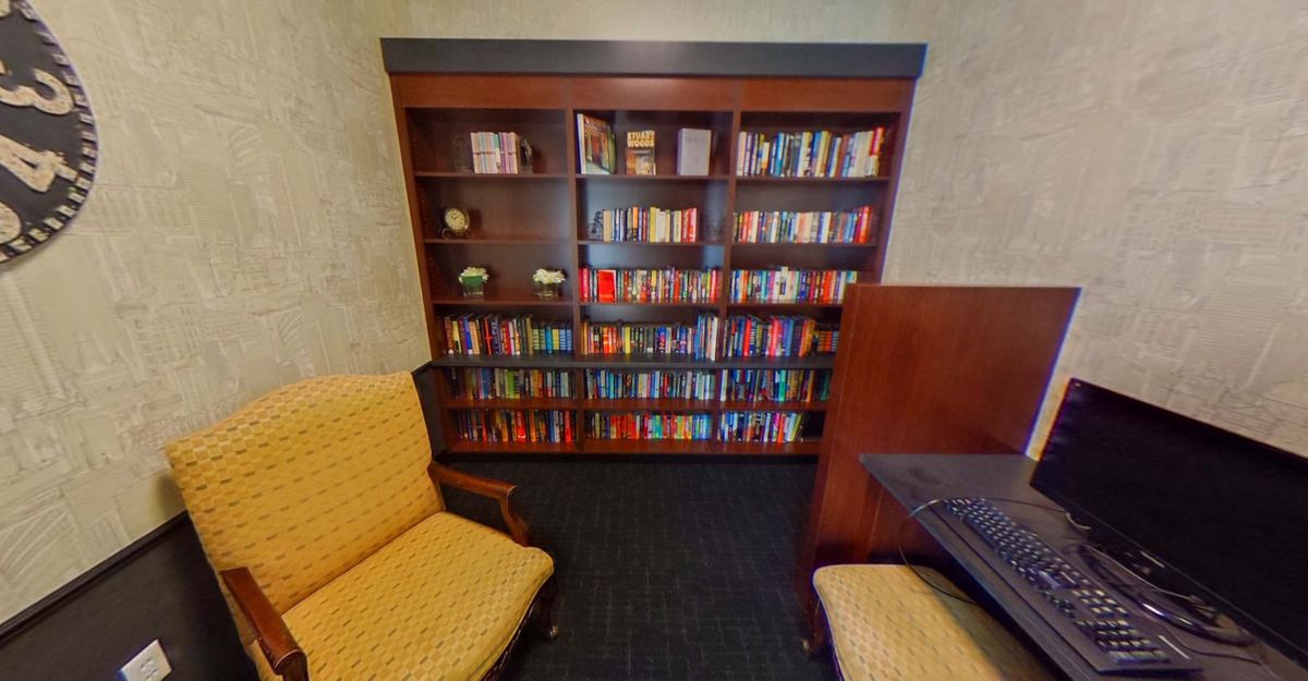 A cozy library corner featuring a wooden bookshelf filled with books and comfortable seating.