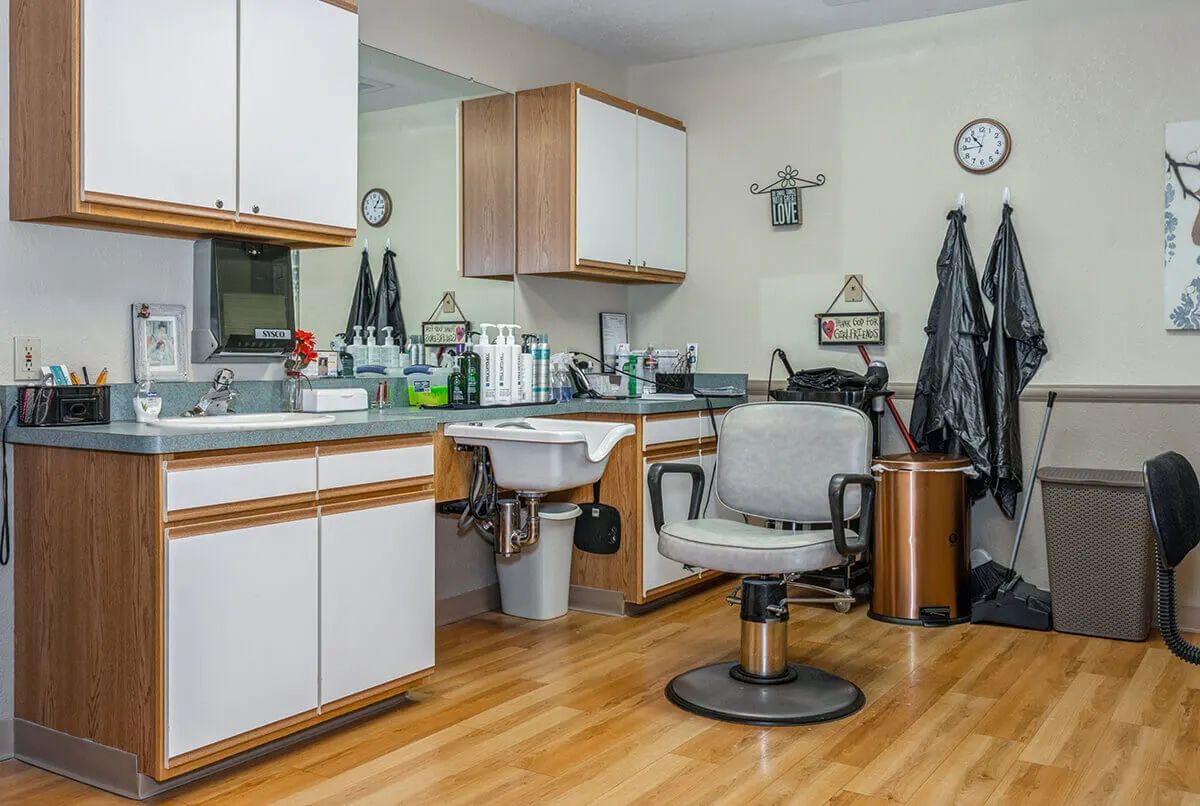 An interior view of a barbershop with a salon chair, mirrors, and hair products on wooden floors.