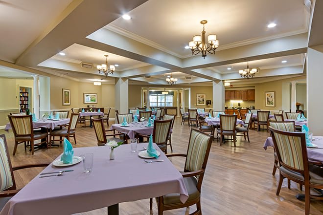 An elegant dining room with neatly arranged tables and chandeliers.