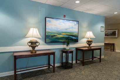 A decorated hallway with lamps and artwork on blue walls.