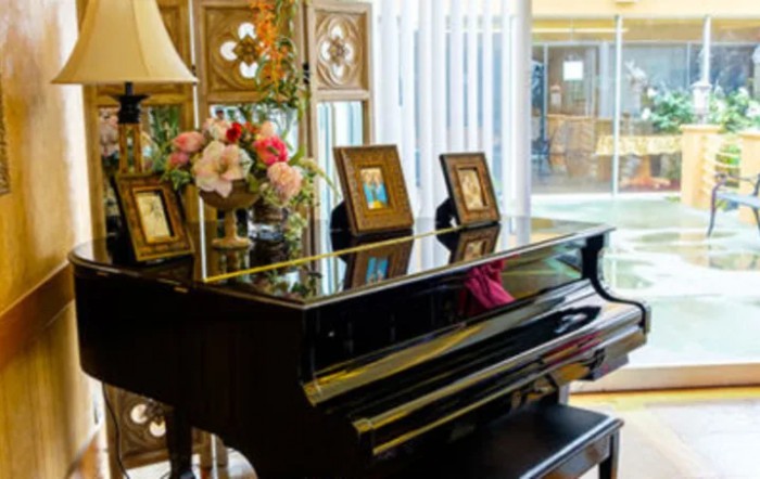 A grand piano adorned with flowers and photo frames in a cozy living room.
