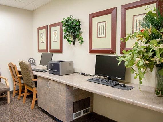 A small office space with desks equipped with computers, a printer, and decorative wall art.