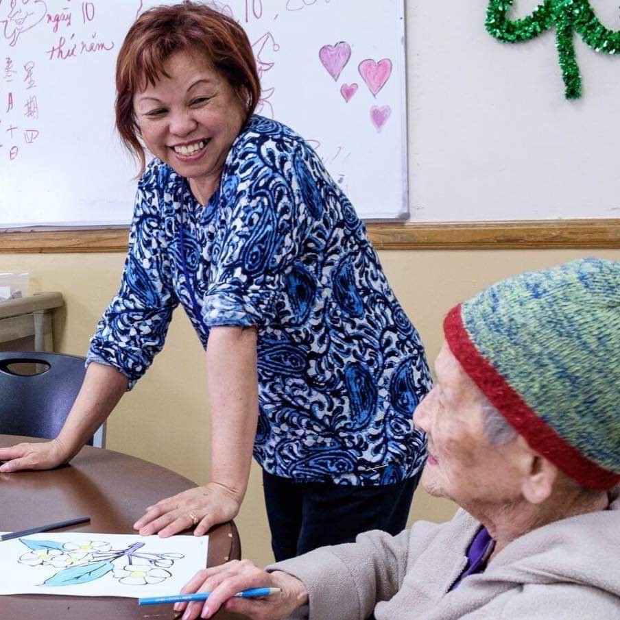 A cheerful interaction between two women during an art activity at a community center.