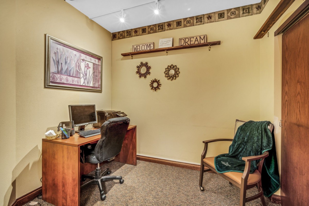 A cozy home office with a computer desk, chair, and decorative wall art.