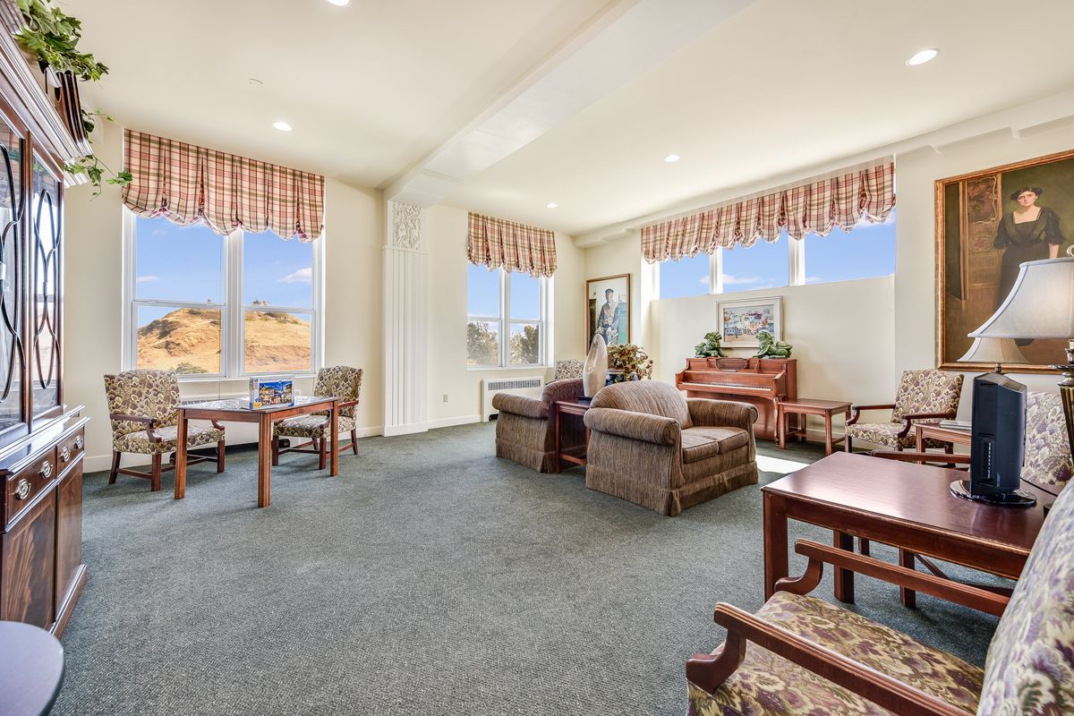 A spacious and well-lit living room featuring comfortable seating, large windows with scenic views, and a cozy atmosphere.