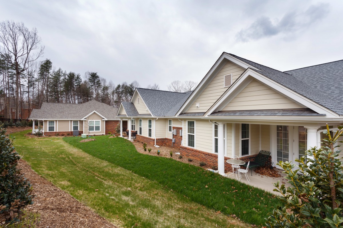 A row of suburban houses with manicured lawns and porches.