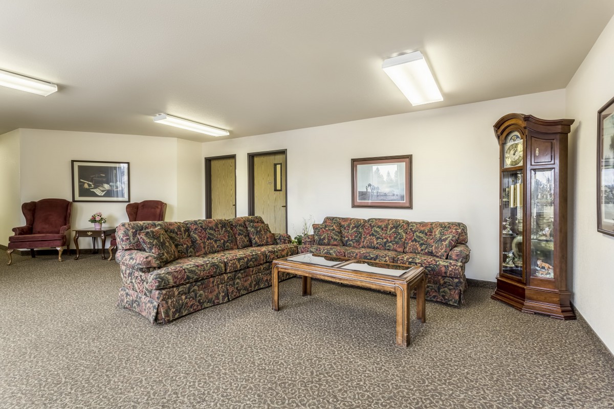 A living room with patterned sofas, a wooden coffee table, carpeted flooring, and wall decorations.