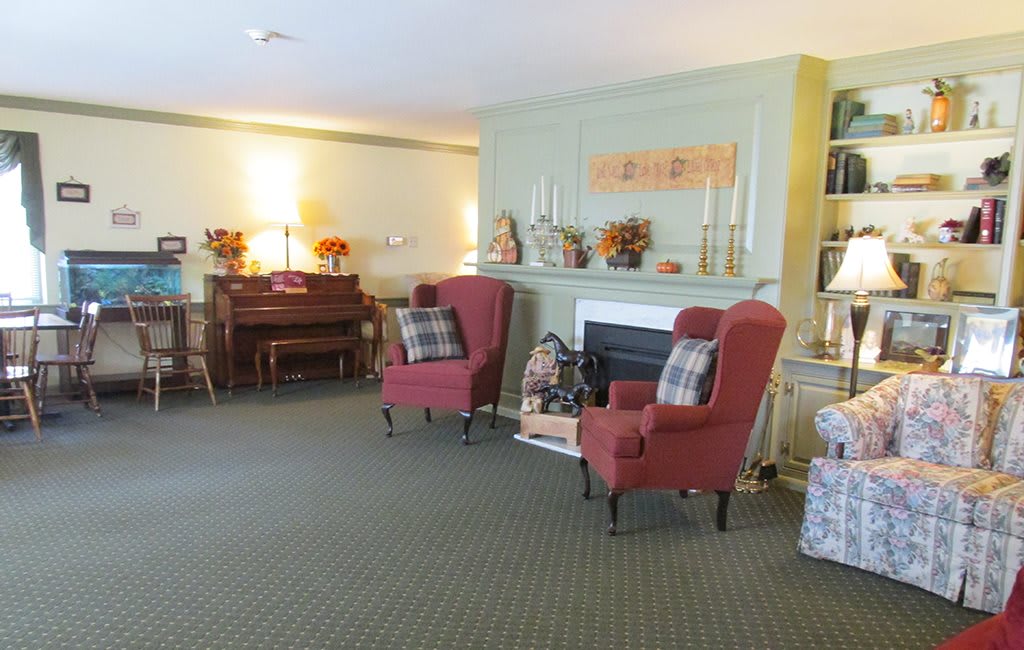 A cozy living room with comfortable armchairs, a fireplace, and a piano.
