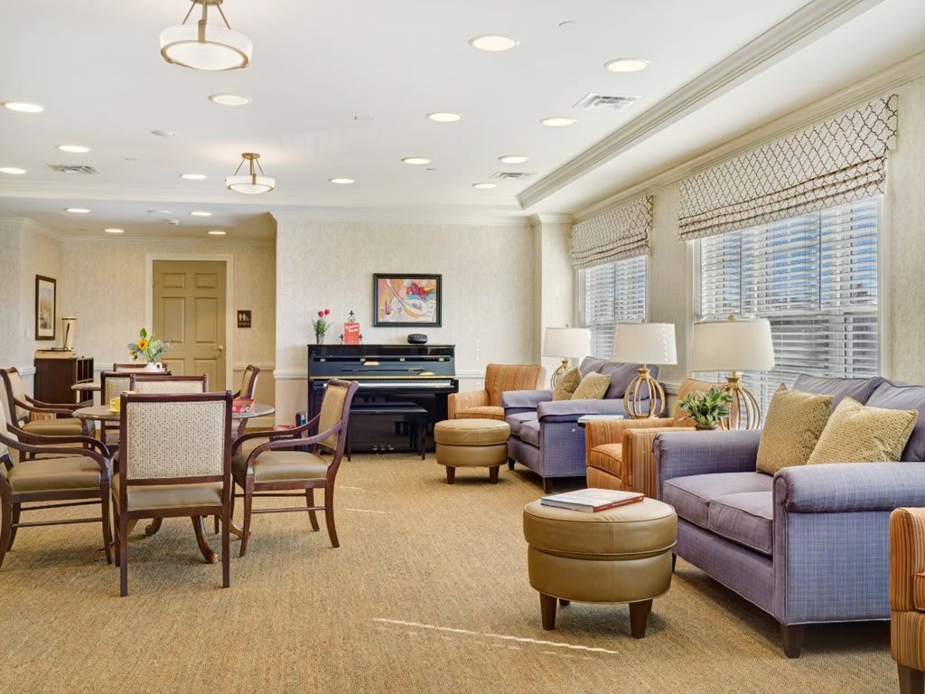 A cozy and spacious living room with comfortable seating, a piano, and ample natural lighting.