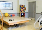 A physical therapy room equipped with various exercise tools and a treatment table.