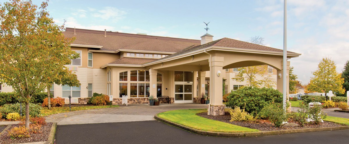A modern building entrance with large windows and well-maintained landscaping.