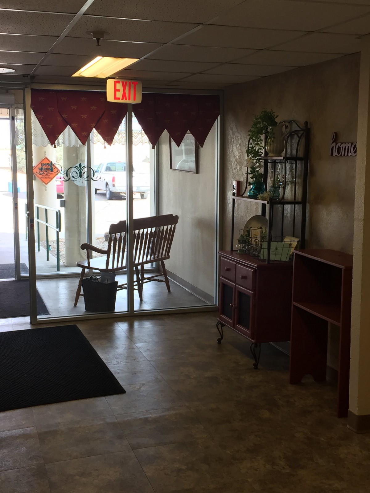 A cozy waiting area with a wooden bench near glass entrance doors.