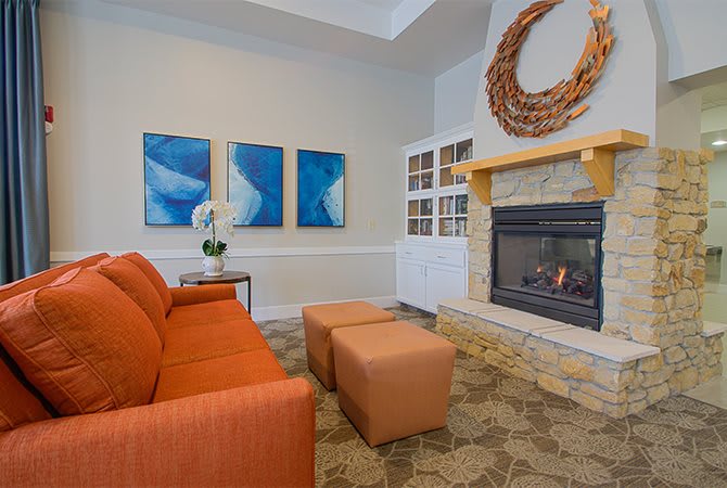 A modern living room with an orange couch, a fireplace, and blue artwork on the wall.