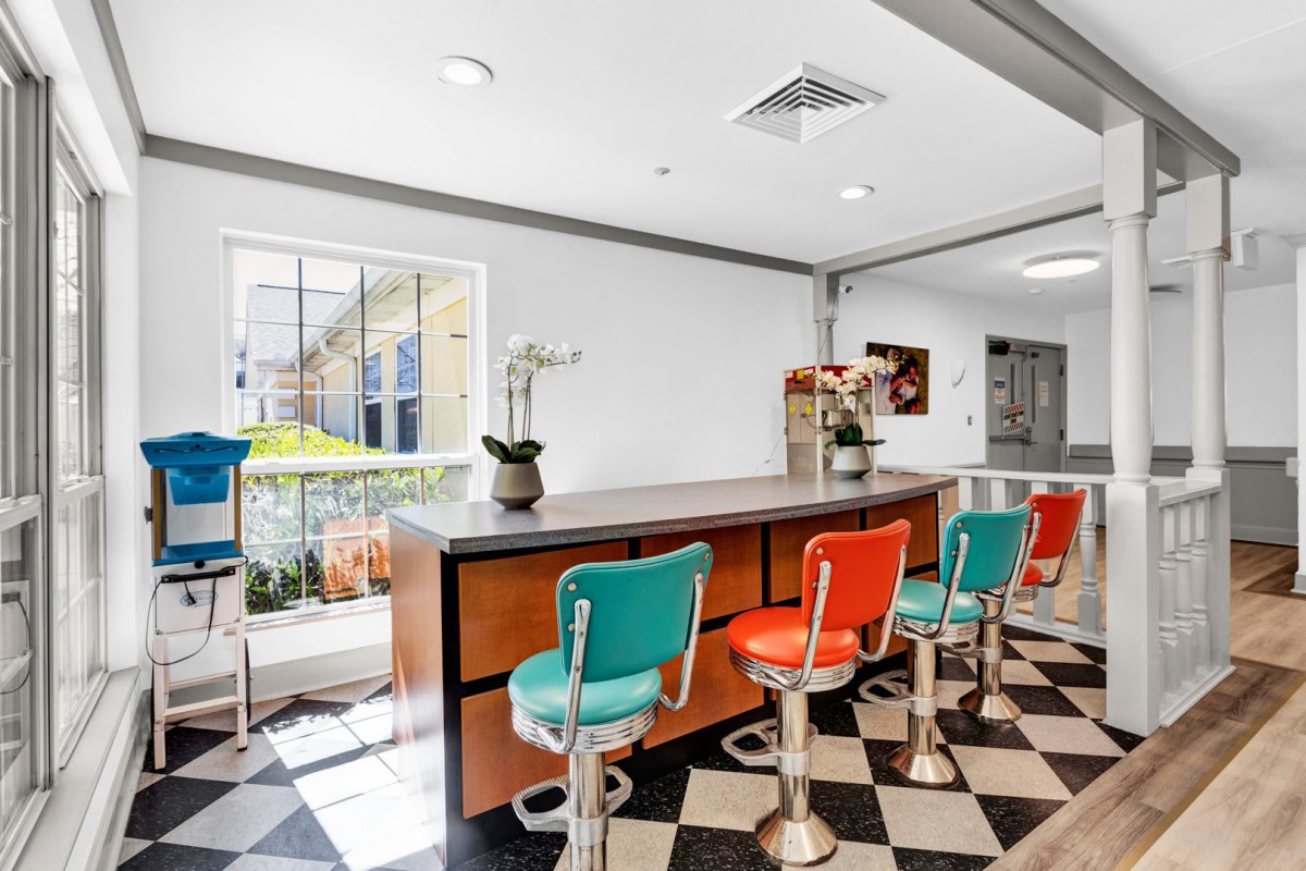 A retro diner with colorful bar stools and a checkered floor.