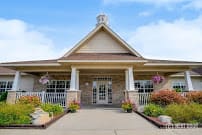 A welcoming building entrance with a front porch and floral decorations.