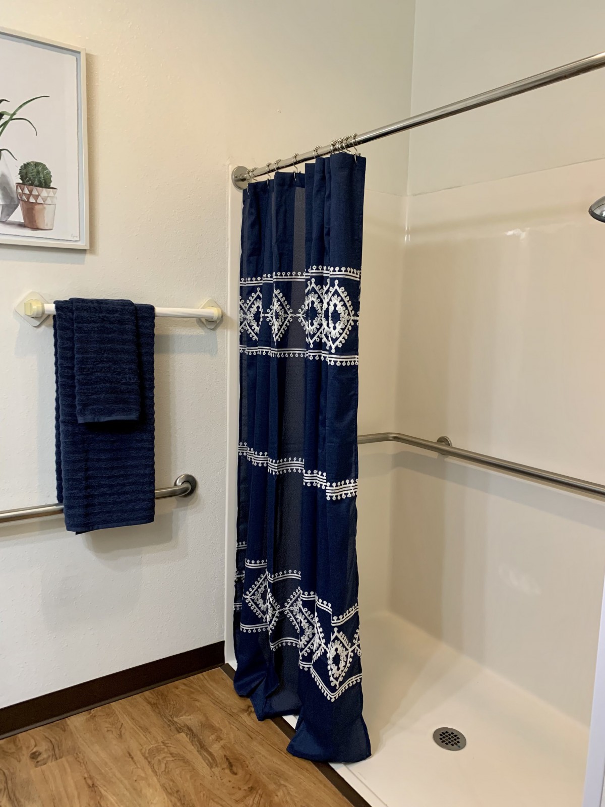 A bathroom featuring a blue and white shower curtain with matching towels on the wall.