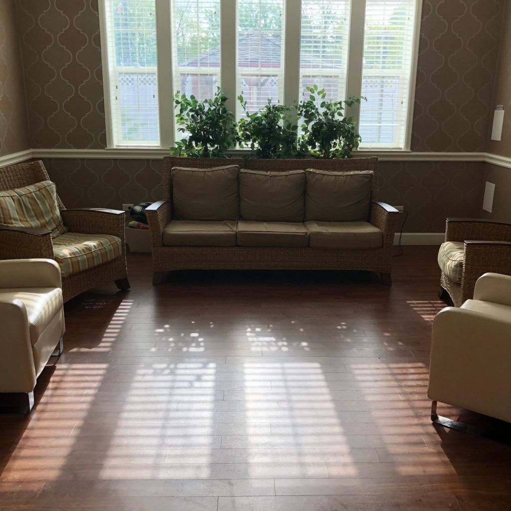 A cozy living room with a sofa, armchairs, and large windows letting in natural light.