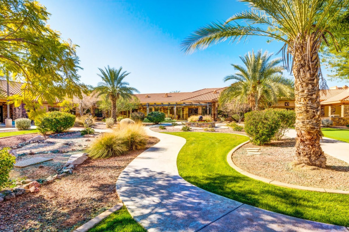 A beautifully landscaped garden with palm trees and a winding pathway on a sunny day.