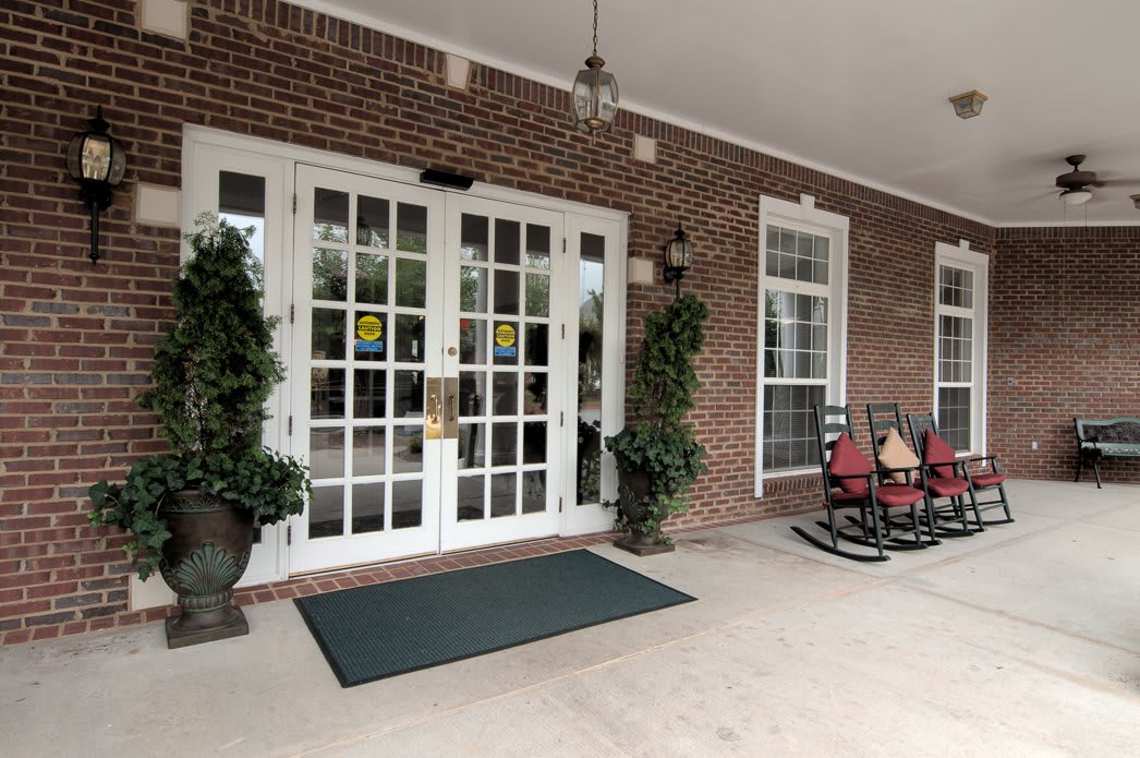 Front entrance with glass doors, potted plants, and seating area.