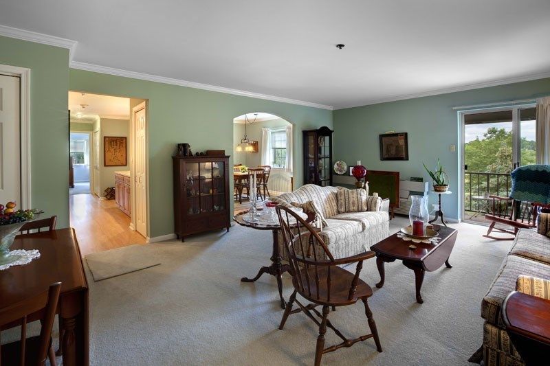 A traditional living room with green walls, featuring a sofa, armchairs, and wooden furniture.