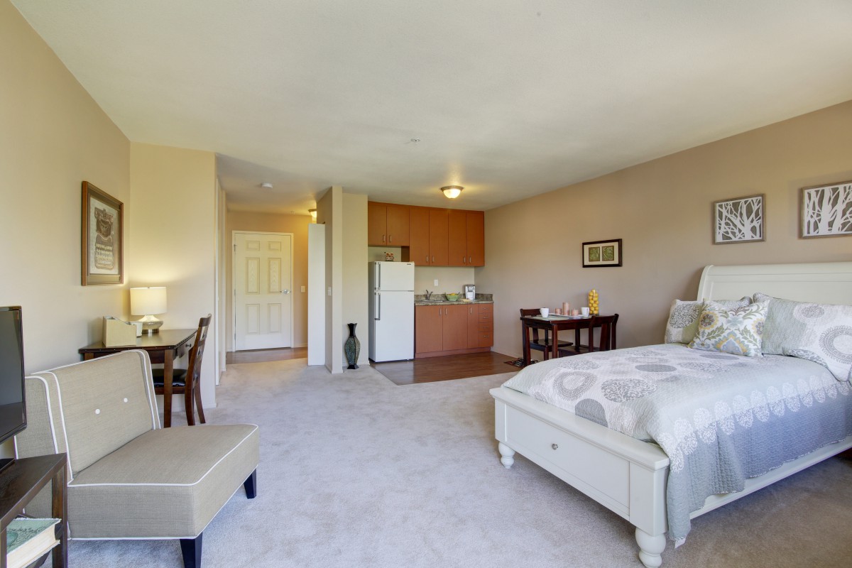 A cozy studio apartment featuring a kitchenette, bed, and dining area.