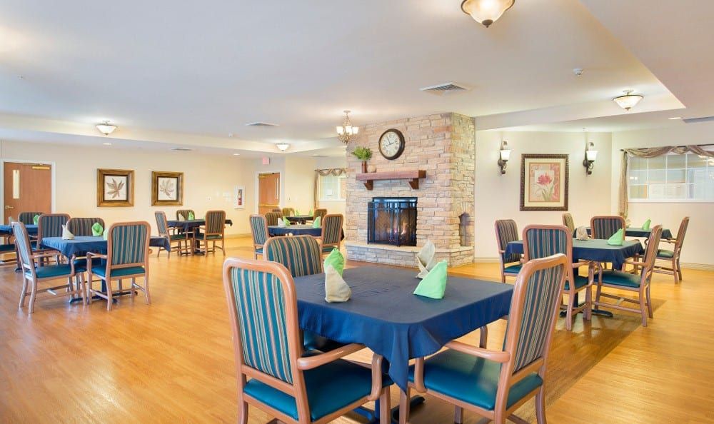 A cozy dining area with neatly arranged tables and a central fireplace.