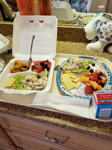 A colorful and nutritious lunch featuring a chicken salad with fresh fruits and a side of assorted melon.