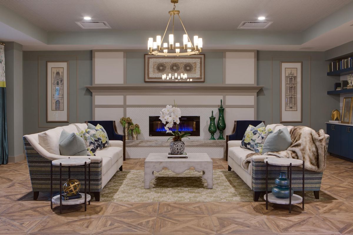 A beautifully designed living room featuring a chandelier, two sofas, a coffee table, and a fireplace.