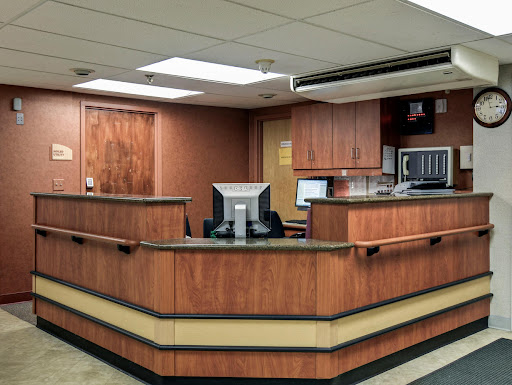A modern reception area in a healthcare setting, featuring wooden cabinetry and a computer workstation.