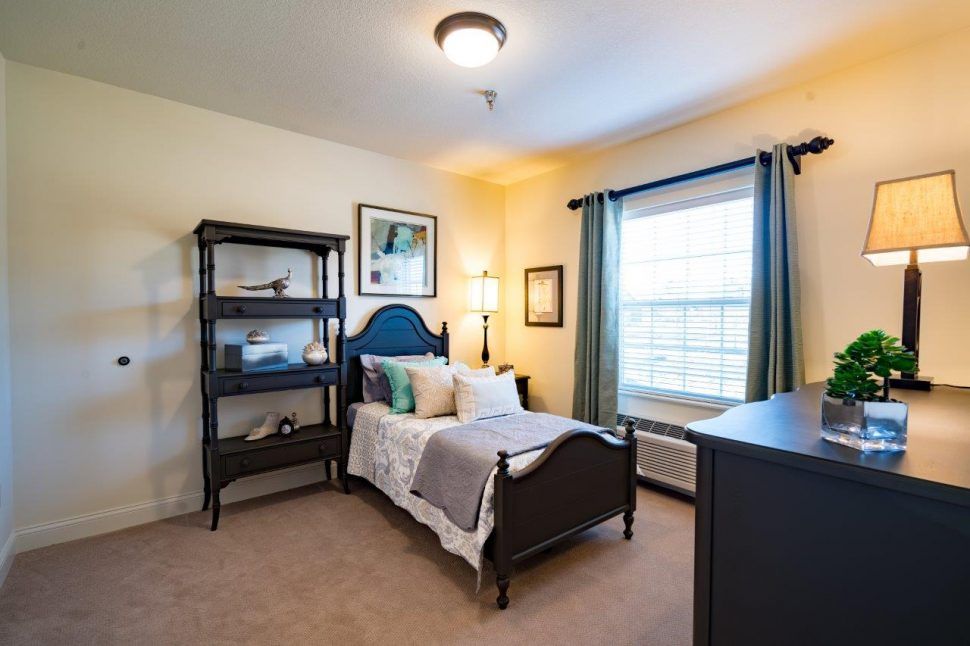 A cozy bedroom with a single bed, bookshelf, and window with curtains.