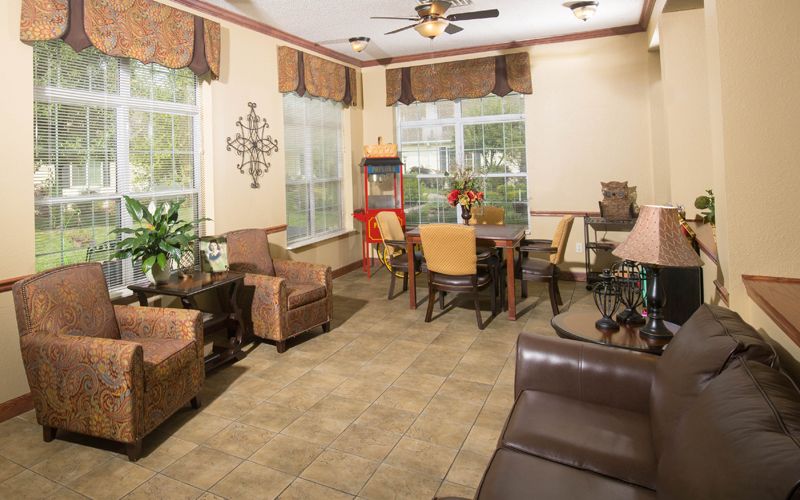 A cozy living room with comfortable seating, large windows, and a popcorn machine.