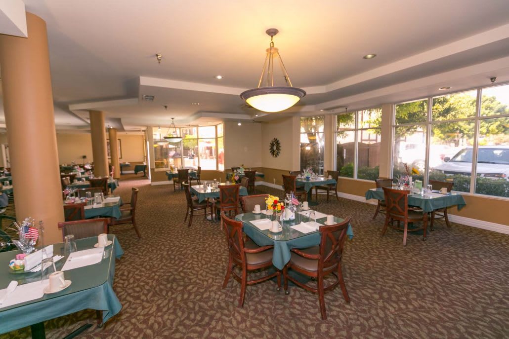 An elegant dining room with neatly arranged tables and chairs, featuring warm lighting and tasteful decor.