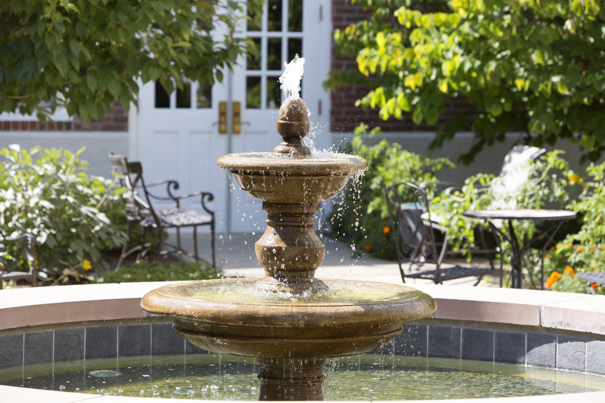 A decorative garden fountain surrounded by lush greenery.