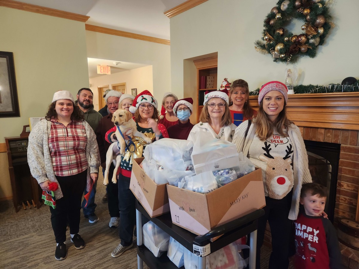 A group of people celebrating Christmas with gifts, wearing Santa hats and festive attire.