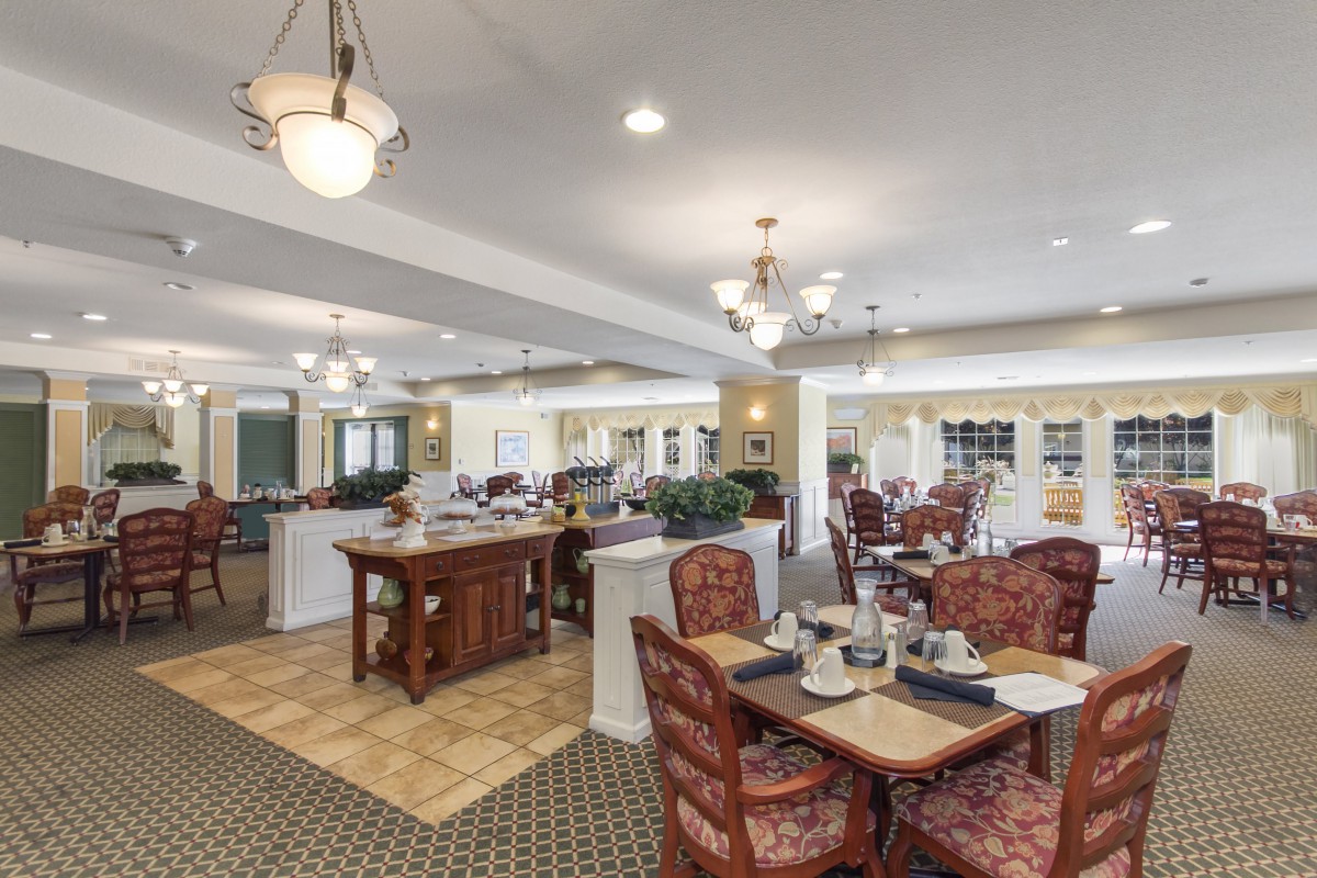 An elegant dining area with tables, chairs, and chandeliers providing a warm ambiance.