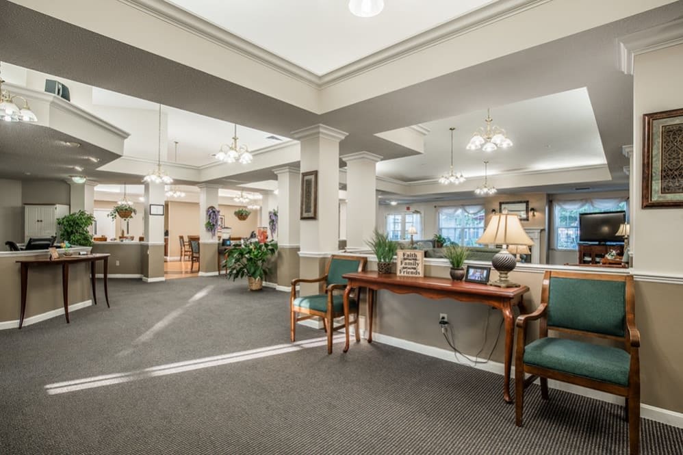 A spacious lobby with traditional furnishings and warm lighting, featuring seating arrangements and decorative elements.