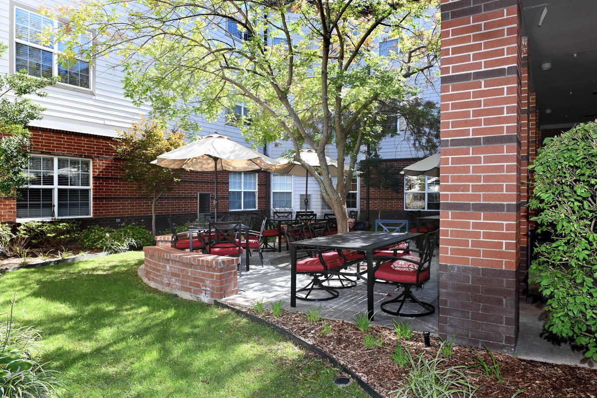A cozy outdoor patio area with seating and umbrellas next to a brick building.