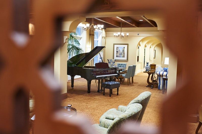 A luxurious lounge featuring a grand piano and elegant furniture.