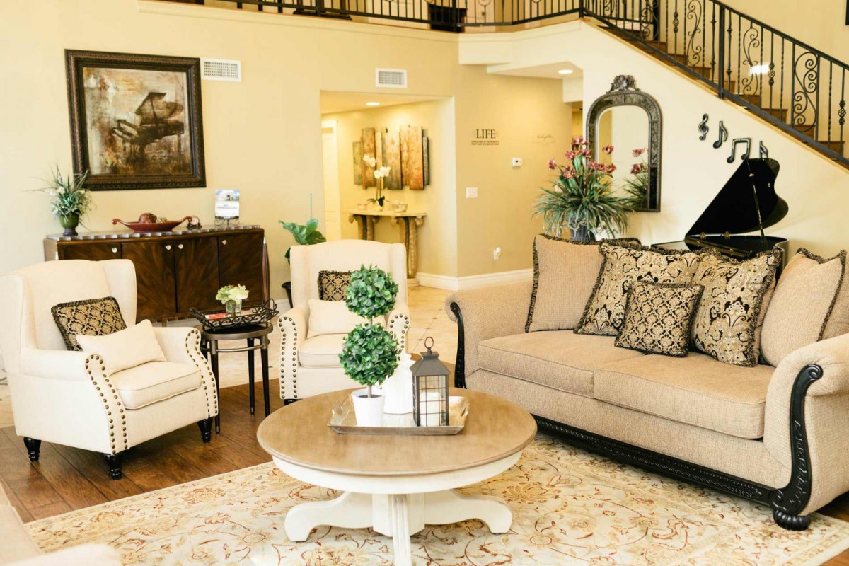 A cozy living room with elegant furniture and tasteful decor, featuring a sofa, chairs, and a round coffee table adorned with plants.