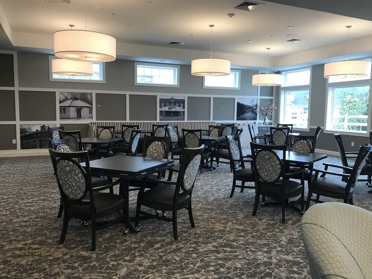 A spacious dining room with multiple tables, chairs, and elegant lighting fixtures.