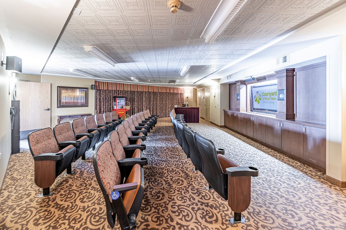 A small theater-style room with rows of cushioned seats and a carpeted floor.