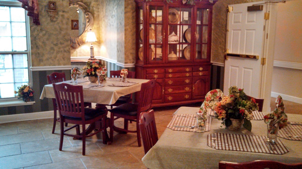 A cozy dining room with elegantly set tables and a china cabinet.