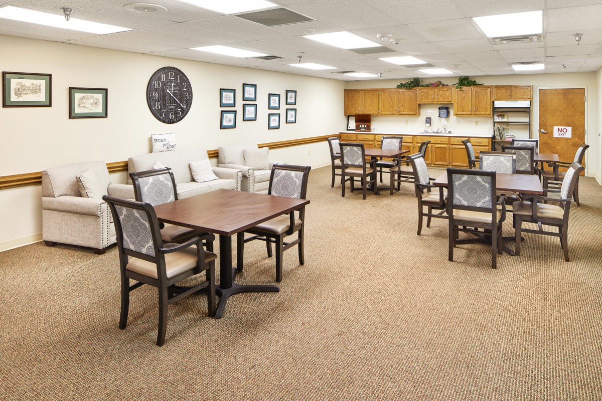 A cozy dining and seating area with a kitchenette in the background.