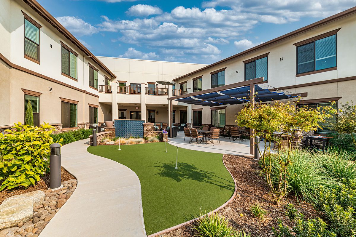 A beautifully landscaped courtyard with a patio area in a modern building complex.